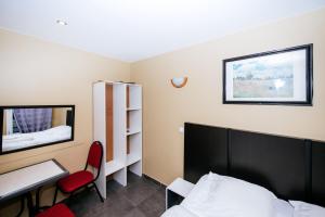 Schlafzimmer mit einem Bett, einem Schreibtisch und einem Spiegel in der Unterkunft Hotel De La Poste in Paris