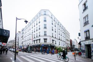 a white building on a city street with a person riding a bike at Hotel De La Poste in Paris