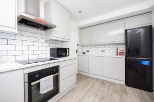 eine Küche mit weißen Schränken und einem schwarzen Kühlschrank in der Unterkunft Modern 2 Bedroom Apartment Brixton Station in London