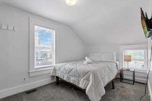 a white bedroom with a bed and two windows at Housepitality - The Marienplatz - Free Parking in Columbus