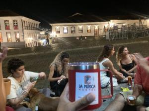 un grupo de personas sentadas alrededor de una mesa por la noche en La Musica Hostel OuroPreto en Ouro Preto