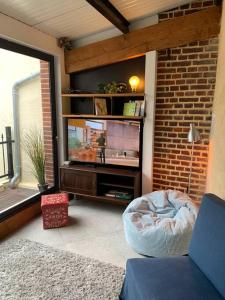 uma sala de estar com uma televisão e uma parede de tijolos em Au cœur du centre historique ! em Beauvais