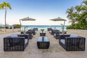 a row of chairs and umbrellas on a beach at The House by Elegant Hotels - All-Inclusive, Adults Only in Saint James