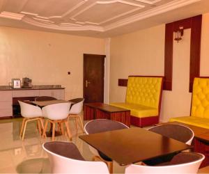 Habitación con sillas, mesas y sillas amarillas. en Bosanic Hotel, en Benin City