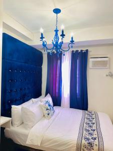 Schlafzimmer mit einem Bett mit blauem Kopfteil und Vorhängen in der Unterkunft CasadeIsabel: Elegant 2BR n Cebu/Washing/Netflix in Cebu City