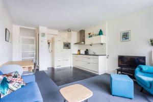 sala de estar con sofá azul y cocina en Newa 1, en Amstelveen