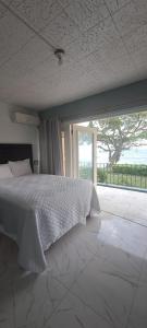 a bedroom with a white bed and a large window at Carib condo in Ocho Rios