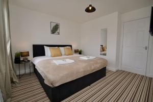 um quarto com uma cama grande e almofadas amarelas em 2Bed Haven - Coventry's Hidden Gem With Free Parking, Sky TV & Netflix em Coventry