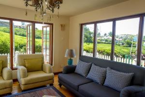 a living room with a couch and chairs and windows at Villa Tea Fields in Nuwara Eliya