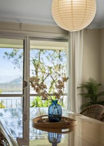 Una mesa con un jarrón azul con flores. en Breathtaking Water Vista - Pool Table, en Empire Bay