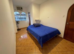 ein Schlafzimmer mit einem Bett mit einer blauen Decke darauf in der Unterkunft Casita en el centro de la ciudad in Iquitos