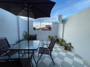 eine Terrasse mit einem Tisch, Stühlen und einem Sonnenschirm in der Unterkunft Casita en el centro de la ciudad in Iquitos