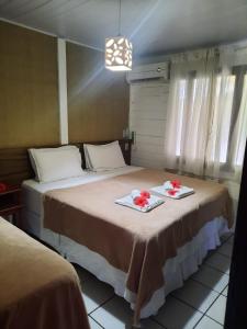 1 dormitorio con 2 camas con flores rojas. en Pousada da Maga, en Fernando de Noronha