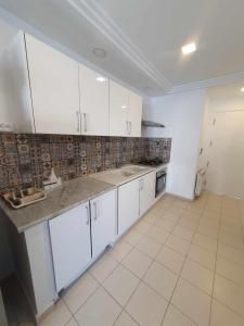 a kitchen with white cabinets and a tiled floor at YoYo House in Sidi Bou Saïd