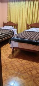 two beds in a room with wooden floors and curtains at Villa hospedaje in Huaraz