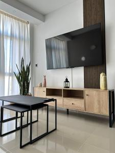 - un salon avec une table et une télévision murale dans l'établissement Departamento Temporario en Comodoro Rivadavia, à Comodoro Rivadavia
