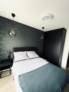 a bedroom with a bed with a black wall at Apartament Bohaterów Westerplatte in Giżycko