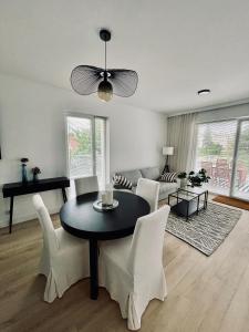 a living room with a black table and white chairs at Apartament Bohaterów Westerplatte in Giżycko