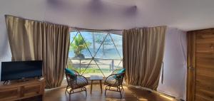 a living room with a large window with chairs and a table at Malipaya Villas in General Luna