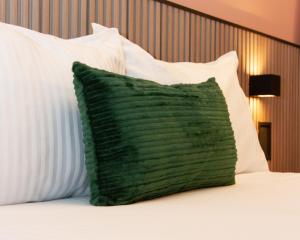 a green pillow sitting on a bed with white pillows at NIU Reforma in Mexico City