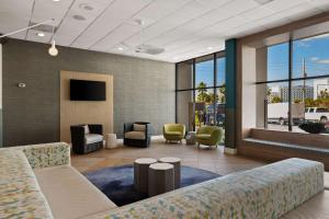 a lobby with a couch and chairs and a tv at Best Western Orlando Gateway Hotel in Orlando