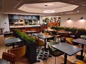 um restaurante com mesas e cadeiras e um bar em Le Carline, Sure Hotel Collection by Best Western em Caen