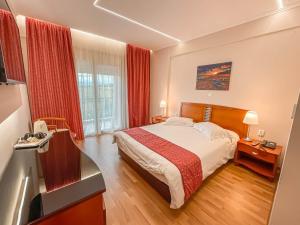 um quarto de hotel com uma cama e uma janela em Ambassador Hotel Thessaloniki em Plagiárion