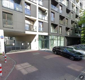 a black car parked in a parking lot in front of a building at Premium Spire Apartment +parking in Warsaw