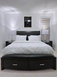 um quarto com uma cama grande com lençóis brancos e almofadas em Voltage em Ottawa