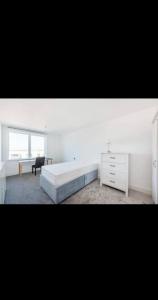 a white bedroom with a large bed and a desk at Amazing Apartment in Harlow