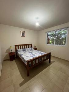 um quarto com uma cama de madeira num quarto com uma janela em Cabaña La Huerta "Traslasierra" em Villa Dolores