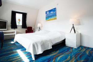 um quarto de hotel com uma cama branca e uma televisão em Hotel Van der Maas em Ootmarsum