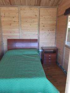 a bedroom with a green bed with a wooden wall at Cabaña Pavachoque in Puente Nacional
