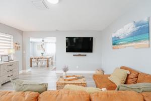 a living room with a couch and a tv on a wall at Home with heated pool close to beach and FLL airport in Fort Lauderdale