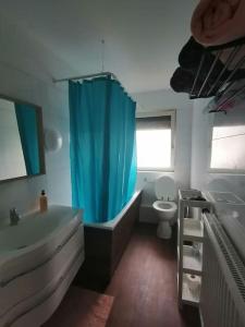 a bathroom with a tub and a toilet and a blue shower curtain at Bright house with a beautiful garden in Isernhagen