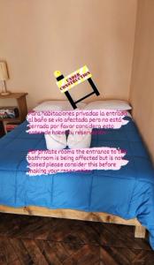 a bed with a blue comforter with a sign on it at Hostal Casa Amarilla Tecámac in Santa Cruz Tecamac