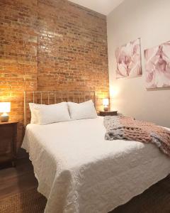 a bedroom with a large bed with a brick wall at Spacious luxury apt in Historic Downtown - OH Amish country in Millersburg
