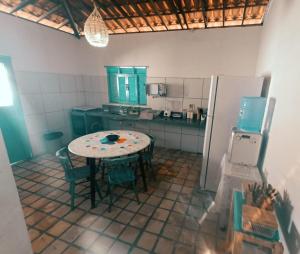 a small kitchen with a table and a refrigerator at CASA PARRACHO Maracajaú in Maxaranguape