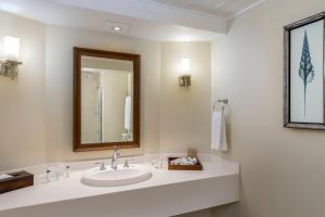 bagno bianco con lavandino e specchio di Turtle Beach by Elegant Hotels - All Inclusive a Christ Church