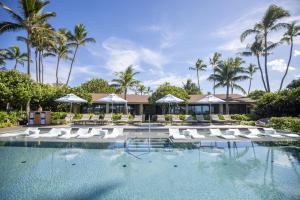 a swimming pool with white lounge chairs and palm trees at Ocean Bungalows at Turtle Bay Resort in Kahuku