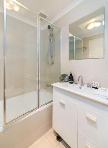 a white bathroom with a shower and a sink at Cosy and convenient leafy apartment 