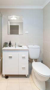 a white bathroom with a toilet and a sink at Cosy and convenient leafy apartment 