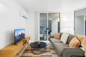 a living room with a couch and a tv at Comfy 2-Bed with Pool and Secure Parking in Brisbane