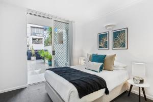 a white bedroom with a bed and a window at Comfy 2-Bed with Pool and Secure Parking in Brisbane