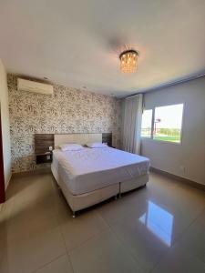 a bedroom with a large bed and a chandelier at Casa Paraiso de Praia in Porto Seguro +4 photos