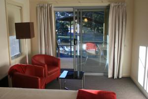 a hotel room with a bed and a chair and a window at Bicheno by the Bay in Bicheno