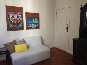 sala de estar con sofá blanco y pinturas en la pared en Apartamento Vista Parcial Mar, en Río de Janeiro