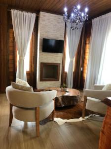 佩德拉阿祖爾的住宿－Recanto do Pimenta，客厅配有两把椅子和壁炉