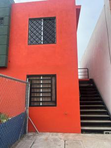 a red building with a staircase and a window at Casa de chapis in Ensenada