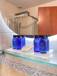 um grupo de garrafas azuis numa prateleira na casa de banho em Ambassador Hotel Thessaloniki em Plagiárion